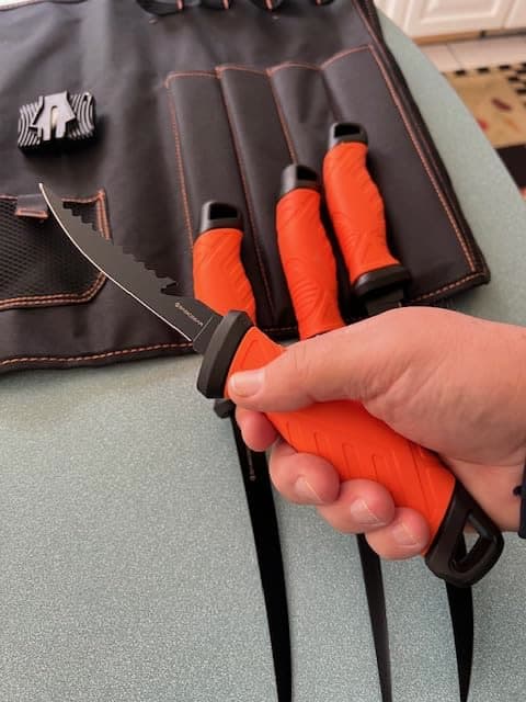 A customer holds a fillet knife from the set over its storage roll